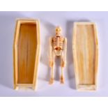 A CONTEMPORARY CARVED BONE SKELETON IN A CASKET. 12 cm x 4.5 cm.