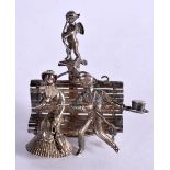 A SILVER MODEL OF AN EDWARDIAN COUPLE ON A PARK BENCH WITH CUPID PERCHED ON A COLUMN. Stamped 910,