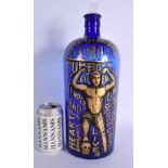 A LOVELY SEQUAHS OIL ADVERTISING BLUE GLASS BOTTLE modelled with a wrestler upon a skull. 37 cm high