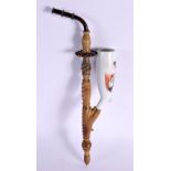 A 19TH CENTURY GERMAN CARVED RHINOCEROS HORN PIPE with porcelain terminal. 30 cm long.
