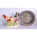 A LARGE ANTIQUE STAFFORDSHIRE FIGURE OF A COW together with a dish. Largest 22 cm x 24 cm. (2)