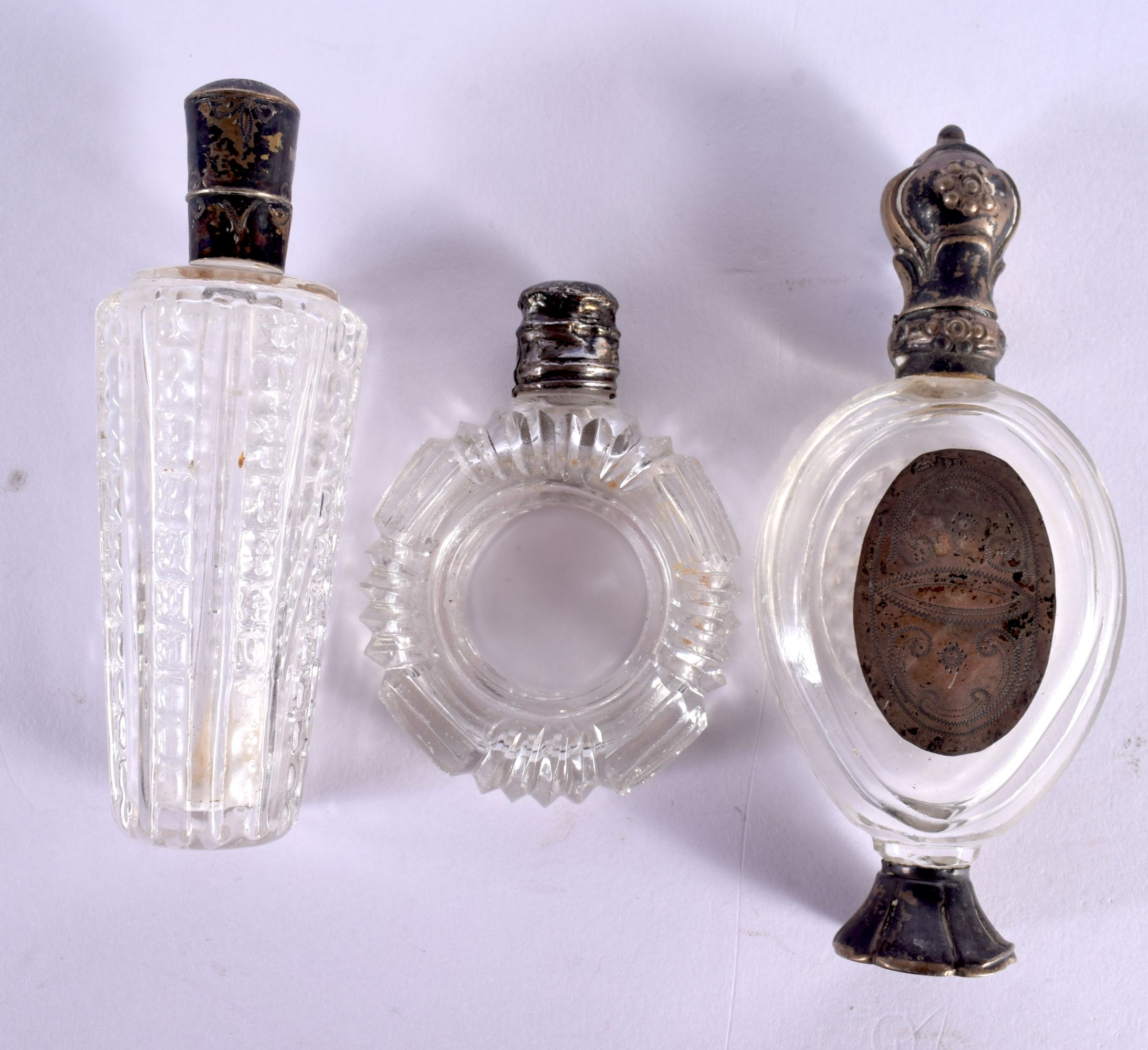 THREE ANTIQUE SILVER TOPPED CRYSTAL GLASS SCENT BOTTLES. Largest 10 cm x 4 cm. (3)