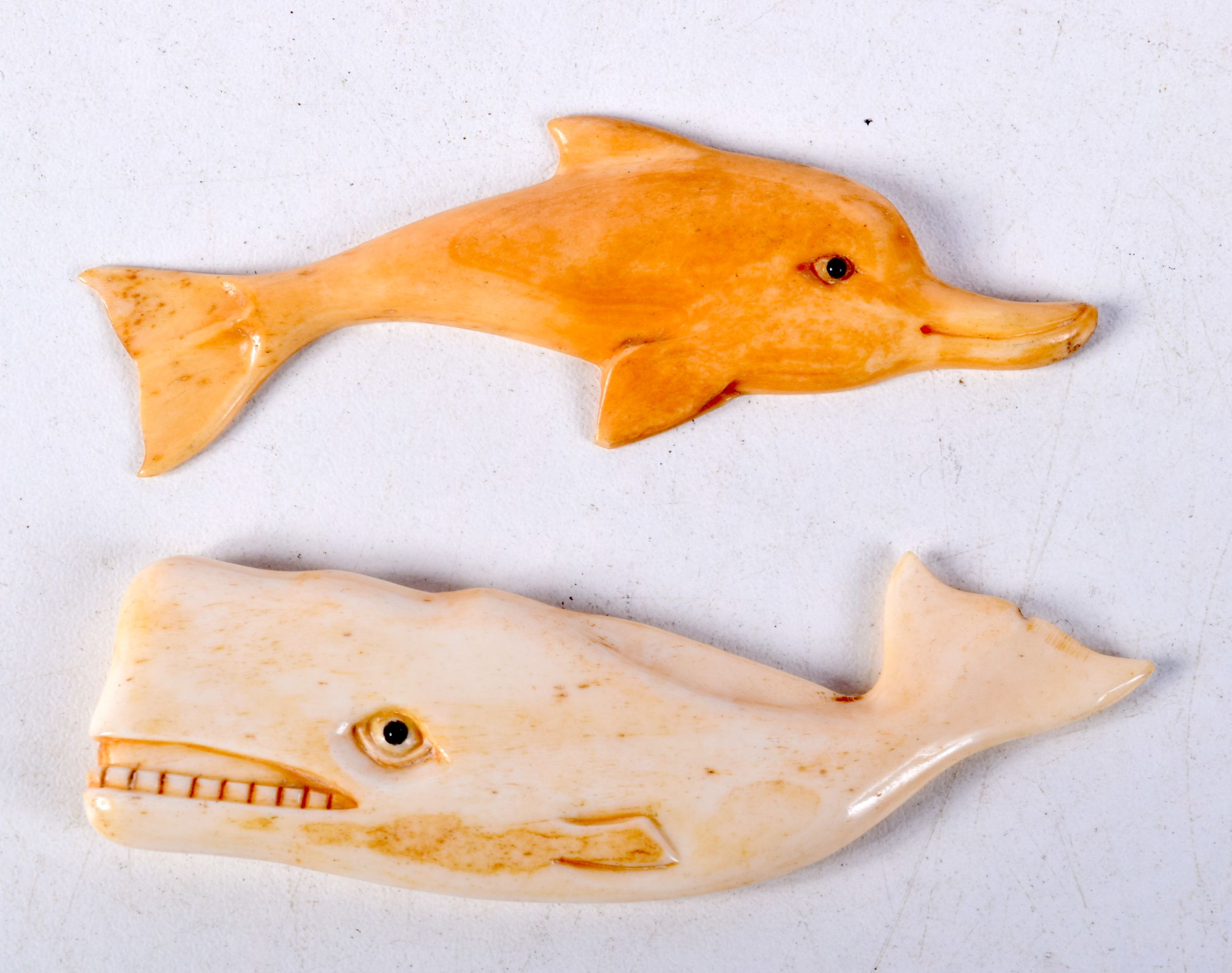 TWO CARVED BONE ANIMALS, A WHALE AND A DOLPHIN. Largest 8.1cm x 2.3cm x 0.6cm (2)