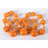 AN AMBER TYPE NECKLACE. 38 grams. 50 cm long, largest bead 1.5 cm wide.