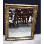 A large wooden and plaster gilt bevelled mirror