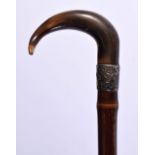 AN ANTIQUE SILVER MOUNTED CARVED RHINOCEROS HORN WALKING CANE. 90 cm long.