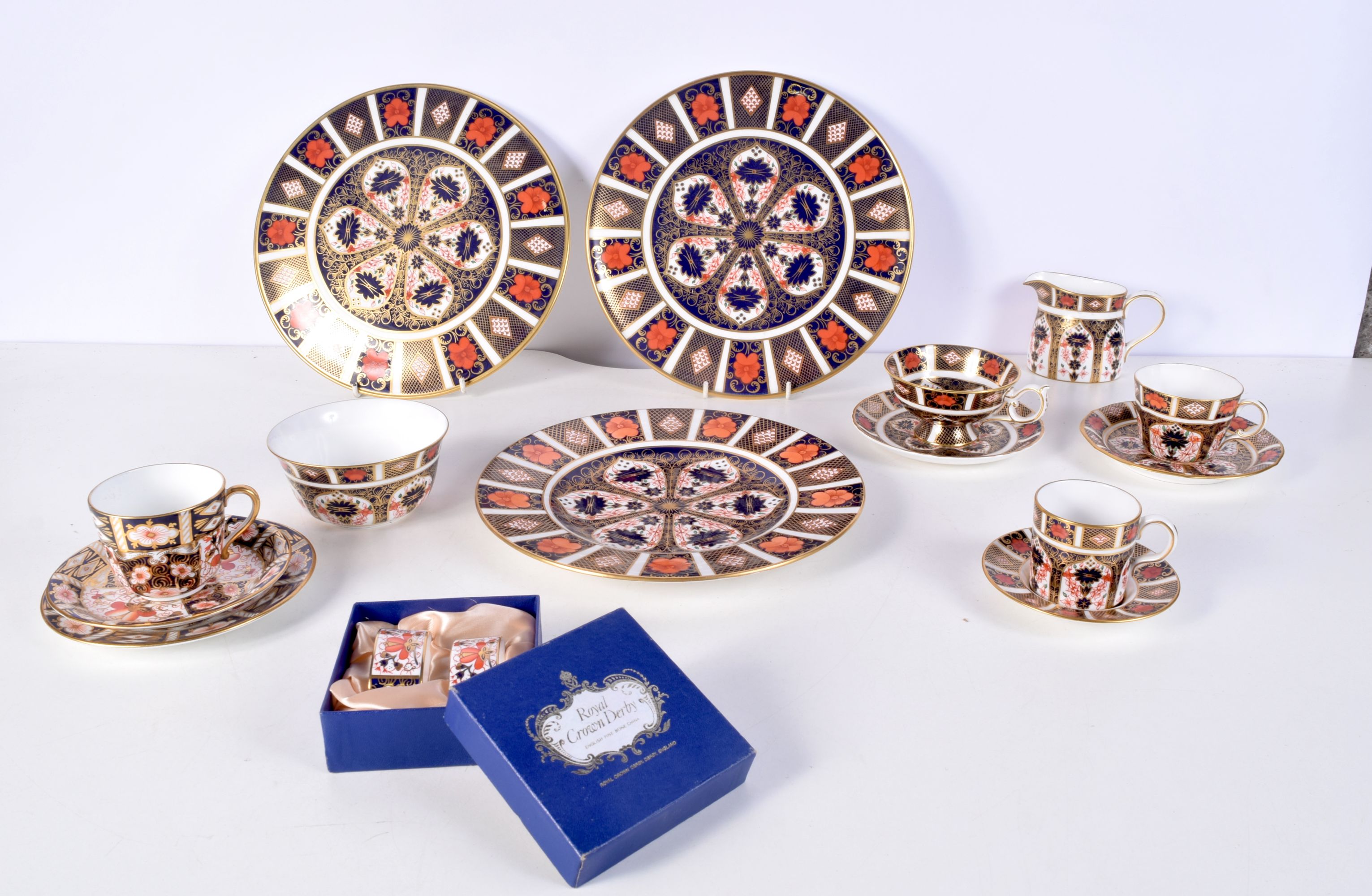 A collection of Royal crown Derby ceramic plates, stands, cups and a boxed napkin set largest 27cm.