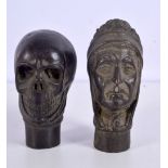 A bronze walking cane handle in the form of a skull together with another handle 8cm (2).