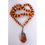 A SILVER BROOCH and an amber necklace. Necklace 70 cm long, pendant 7.75 cm x 3 cm. (2)