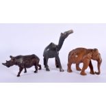 AN ANTIQUE MIDDLE EASTERN CARVED RHINOCEROS HORN FIGURE OF A CAMEL together with two treen animals.
