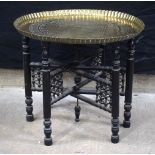 An Islamic brass table on a folding carved ebonised legs 51 x 60 x 60 cm