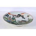 A Chinese porcelain Famille Verte dish decorated with figures 22 cm diameter.