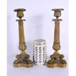 A PAIR OF 19TH CENTURY FRENCH GILT BRONZE EMPIRE CANDLESTICKS with acanthus capped stems, supported
