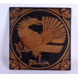 A 19TH CENTURY ARTS AND CRAFTS LACQUERED WOOD PANEL depicting a standing bird. 21 cm square.