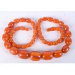 AN ORANGE AMBER TYPE NECKLACE. 88 grams. 72 cm long, largest bead 3 cm x 2 cm.