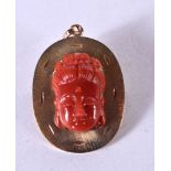 A 14CT GOLD AND CORAL BROOCH/PENDANT. THE CORAL IN THE FORM OF A BUDDHA HEAD. Stamped 14K, 4.6cm x