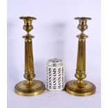 A PAIR OF 19TH CENTURY FRENCH EMPIRE GILT METAL CANDLESTICKS with reeded stems. 27 cm high.