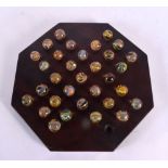 A SET OF ANTIQUE SOLITAIRE GLASS MARBLES. Board 22 cm wide. Marble 1 cm approx wide. (qty)