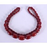 A CHERRY AMBER TYPE NECKLACE. 75 grams. 80 cm long, largest bead 2.75 cm x 1.5 cm.