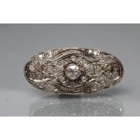 A DIAMOND BROOCH, the pierced oval panel centred by a collet set stone of approximately 0.25cts