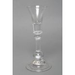A CORDIAL GLASS, c.1710, the trumpet bowl with solid base on basal knop and heavy baluster stem,