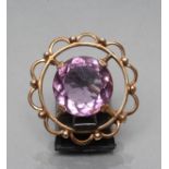 AN AMETHYST BROOCH, the circular facet cut stone claw set to an unmarked open scroll mount (Est.