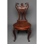 A VICTORIAN MAHOGANY HALL CHAIR, the carved and pierced waisted back with eagle head finials,