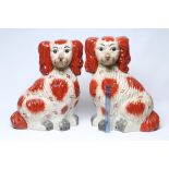 AN UNUSUALLY LARGE PAIR OF STAFFORDSHIRE STYLE POTTERY SPANIELS, modern, with painted iron red