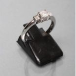 A THREE STONE DIAMOND RING, the princess cut stones point and collet set to a plain white shank,