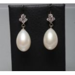 A PAIR OF PEARL DROP EARRINGS, the large tear shaped white pearls peg set to a quatrefoil diamond