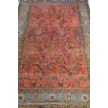 AN ANTIQUE PERSIAN RUG, the soft brick red field with song birds on flowering branches in shades