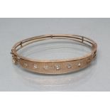 AN EDWARDIAN STIFF HINGED BANGLE, the upper section gypsy set with seven old cut diamonds with