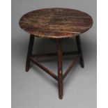 A STAINED PINE CRICKET TABLE, 19th century, the circular plank top on chamfered splayed supports