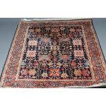 A PERSIAN WOOL RUG, modern, the navy blue field with boldly executed symmetrical foliate pattern