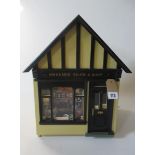 A doll's house village shop, of painted wood construction, with well filled display window, external