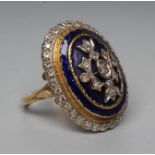 A DIAMOND AND ENAMEL DRESS RING, the large oval boss centred by a panel of point set stones on a