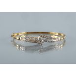 A DIAMOND STIFF HINGED BANGLE, the open scroll upper section pave set with numerous small round
