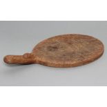 A ROBERT THOMPSON OAK CHEESE BOARD of oval form with carved mouse trademark in high relief to the