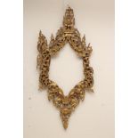 A CARVED AND GILT WOOD INDIAN FRAME of arched oblong form, carved and pierced with flower heads