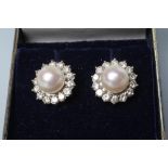 A PAIR OF PEARL AND DIAMOND CLUSTER EAR STUDS, the central peg set cultured pearl within a border of
