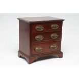 A MAHOGANY MINIATURE CHEST, early 20th century, of two short and two long drawers with oval brass