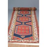 A KAZAK WOOL RUNNER, the indigo field with five linked guls in blue, red and ivory, the red