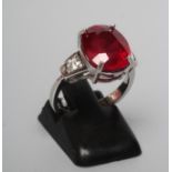 A RUBY RING, the oval facet cut stone of approximately 7.7cts, claw set to shaped shoulders each set