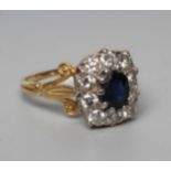 A SAPPHIRE AND DIAMOND CLUSTER RING, the cushion cut sapphire claw set to a border of ten round