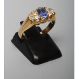 A SAPPHIRE AND DIAMOND RING, the oval facet cut sapphire flanked by two trios of small old cut