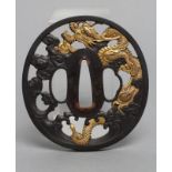A JAPANESE RYU TSUBA, pierced shakudo with details in yellow metal depicting a dragon amid clouds, 3