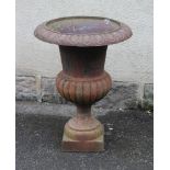 A VICTORIAN CAST IRON URN of half fluted campana form with ovolu rim, waisted socle and square base,