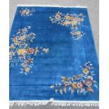 A CHINESE WASHED AND FRINGED BLUE GROUND RUG, modern, with scattered floral sprays in pink, pale