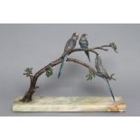 AN ART DECO COLD PAINTED BRONZE TRIO OF BUDGERIGARS, all perched upon a leafy branch fixed to an