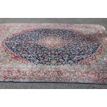 A PERSIAN CARPET, the puce field with repeating flower pattern in shades of blue, green and ivory